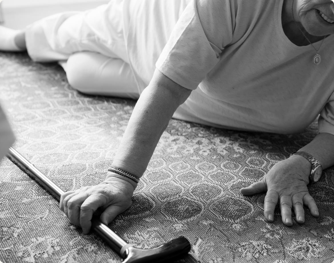 An older person on the floor after a fall, with a walking stick beside them