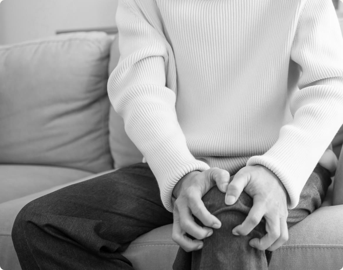 A person seated with both hands resting over a sore knee