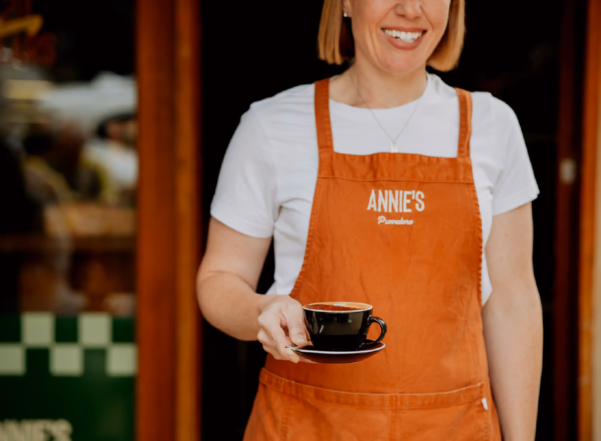 Annie's Provedore wait staff with orange apron holding a coffee