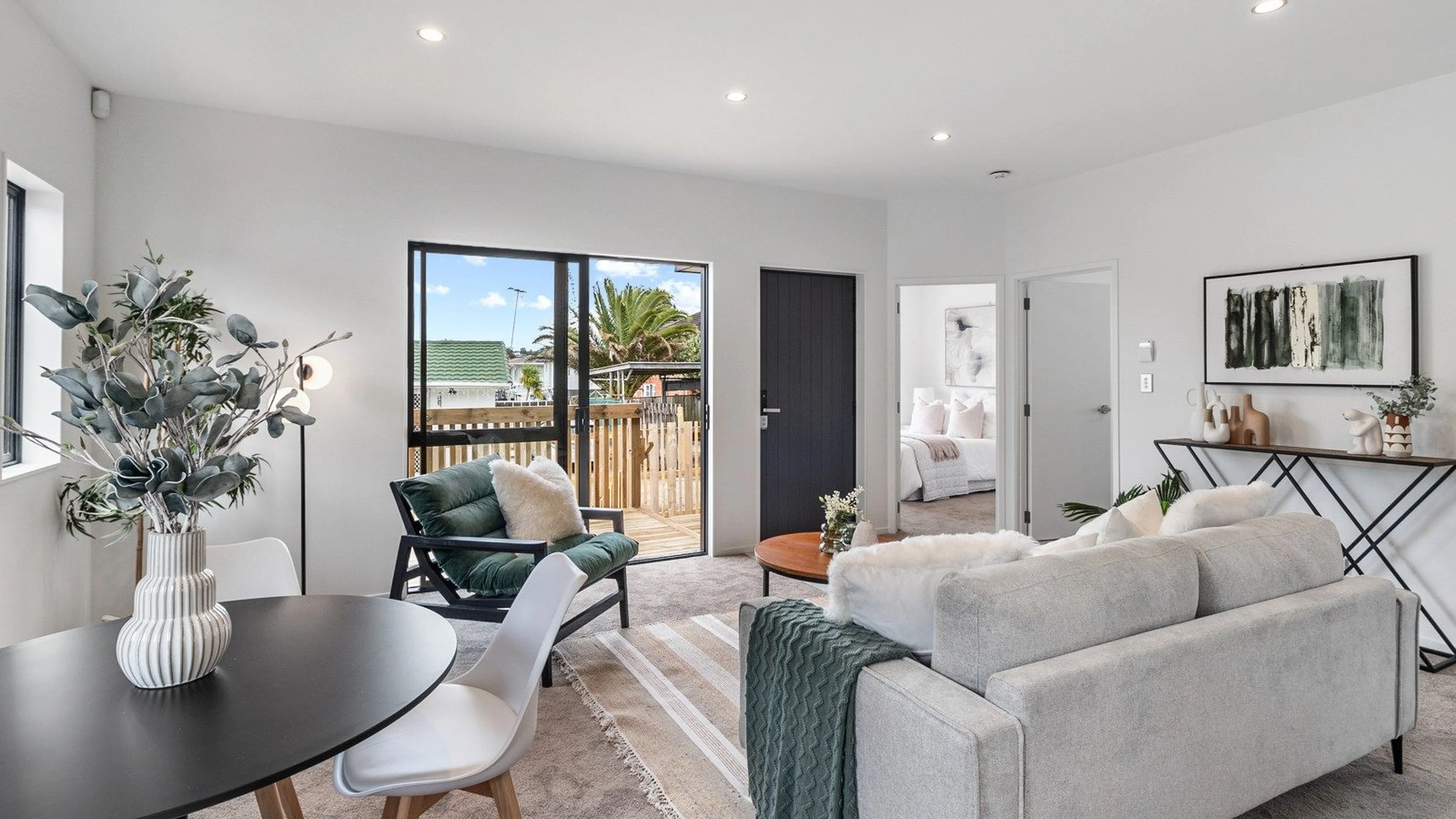 Open plan living and dining opening to the deck in an Eden Group home at Woodward Avenue, Mangere Bridge