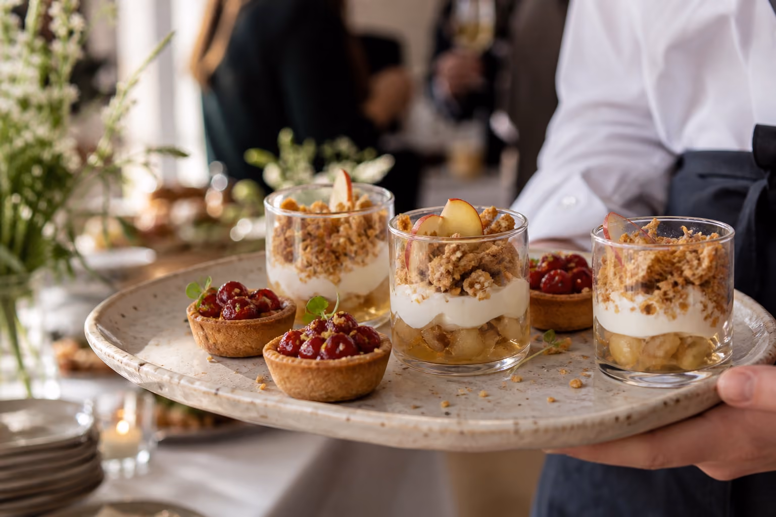 Kleine desserts met fruit, kruimels en romige vulling op een schaal.