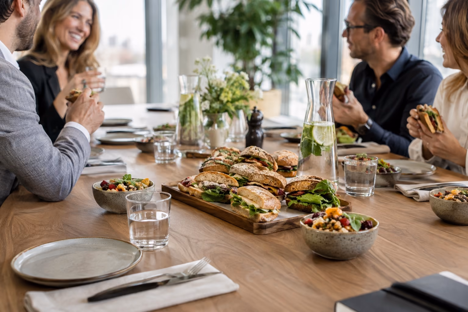 Broodjes en salades staan klaar naast servies in een vergaderruimte.