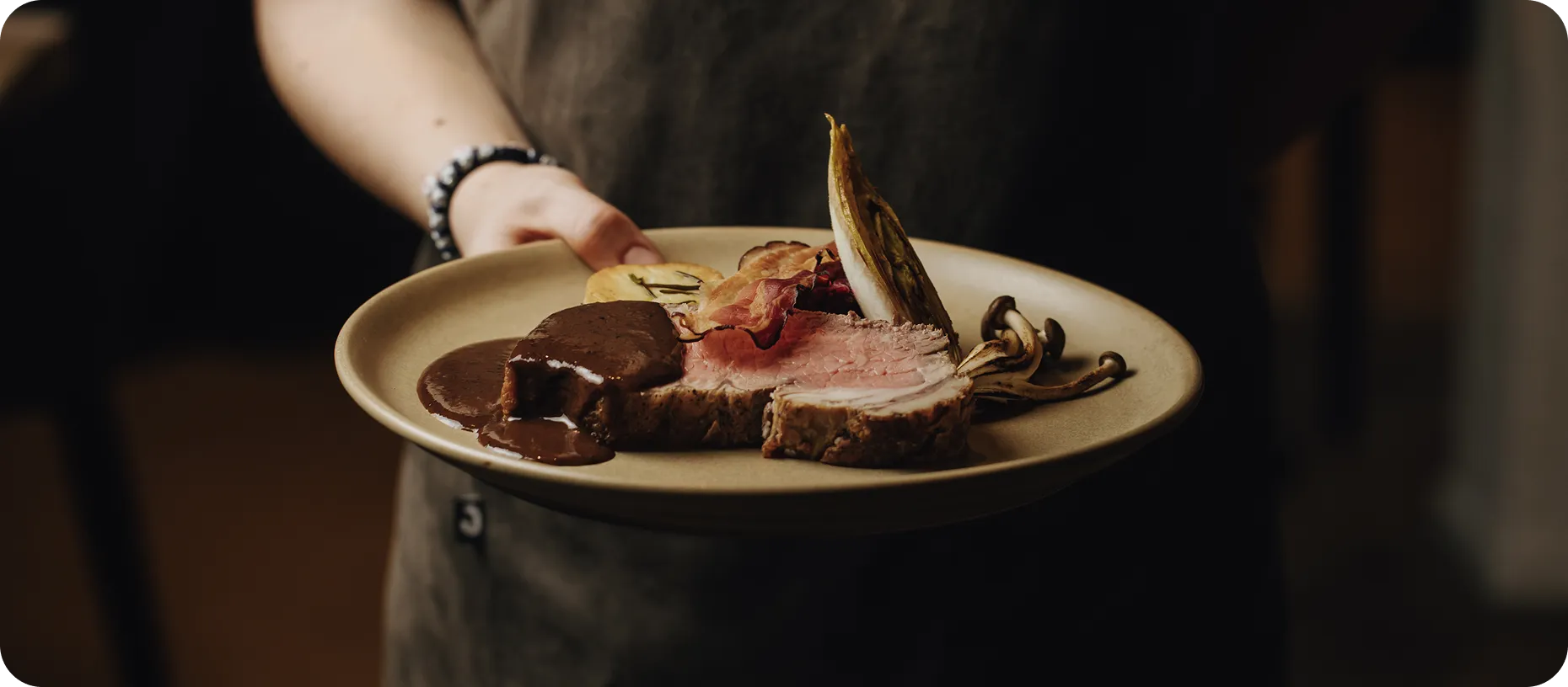Man met schort die een bord eten vast houdt