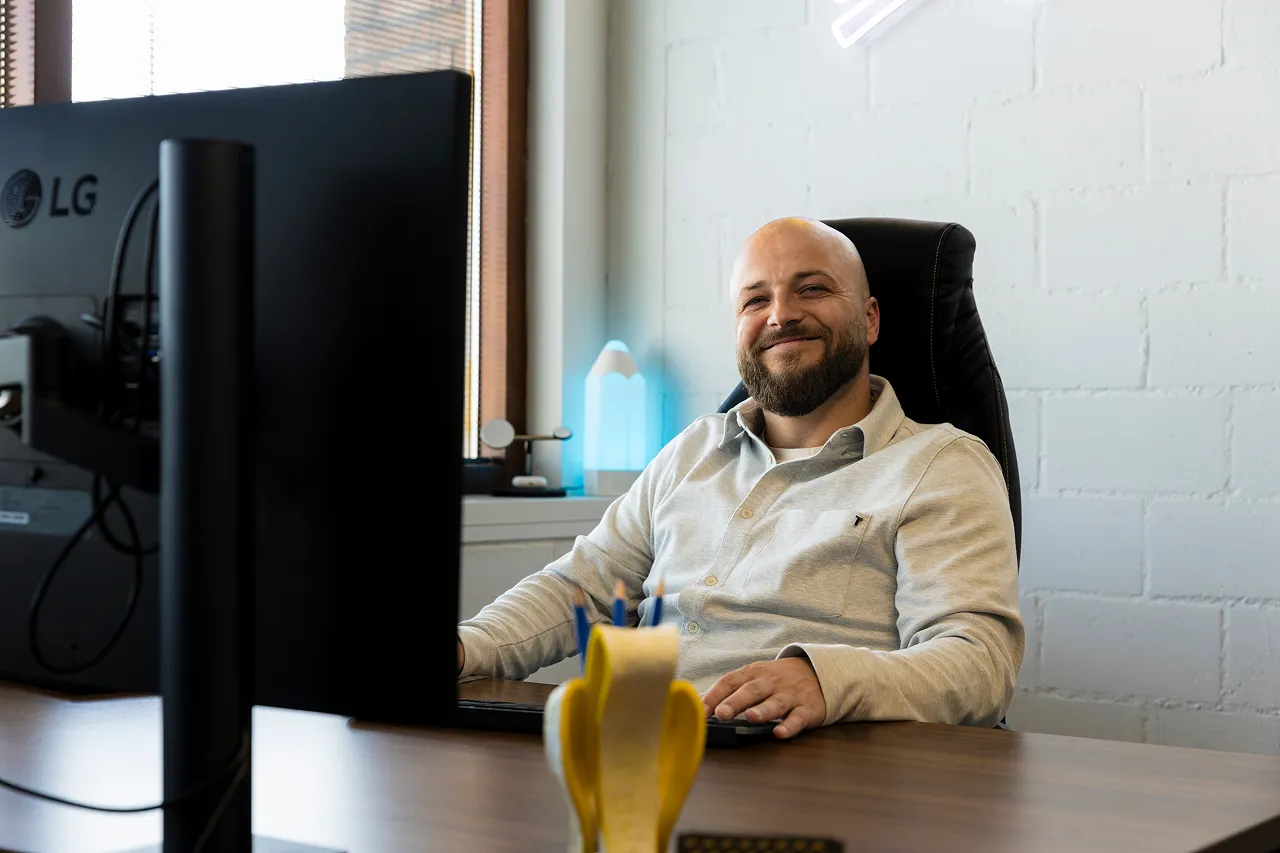 Een medewerker van Brandlos zit achter zijn computer en lacht