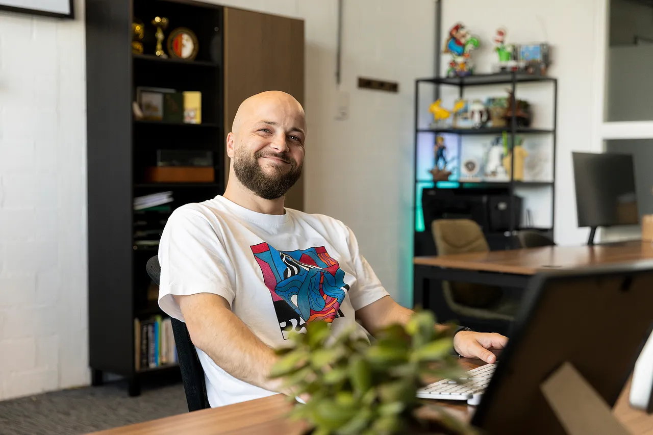 Een medewerker van Brandlos lacht en zit achter zijn computer