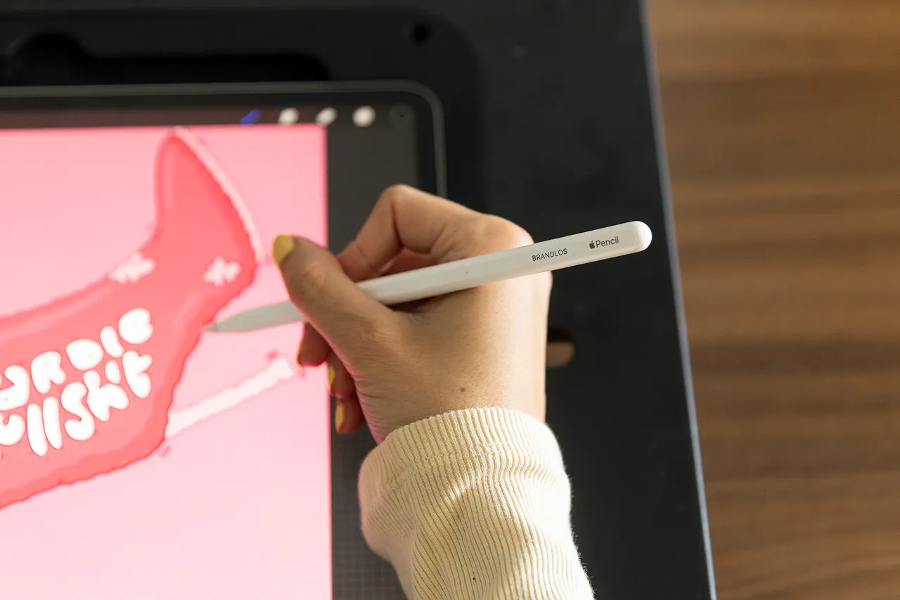 Een medewerker van Brandlos schrijft of tekent op de iPad met een Apple Pencil waar Brandlos op staat.