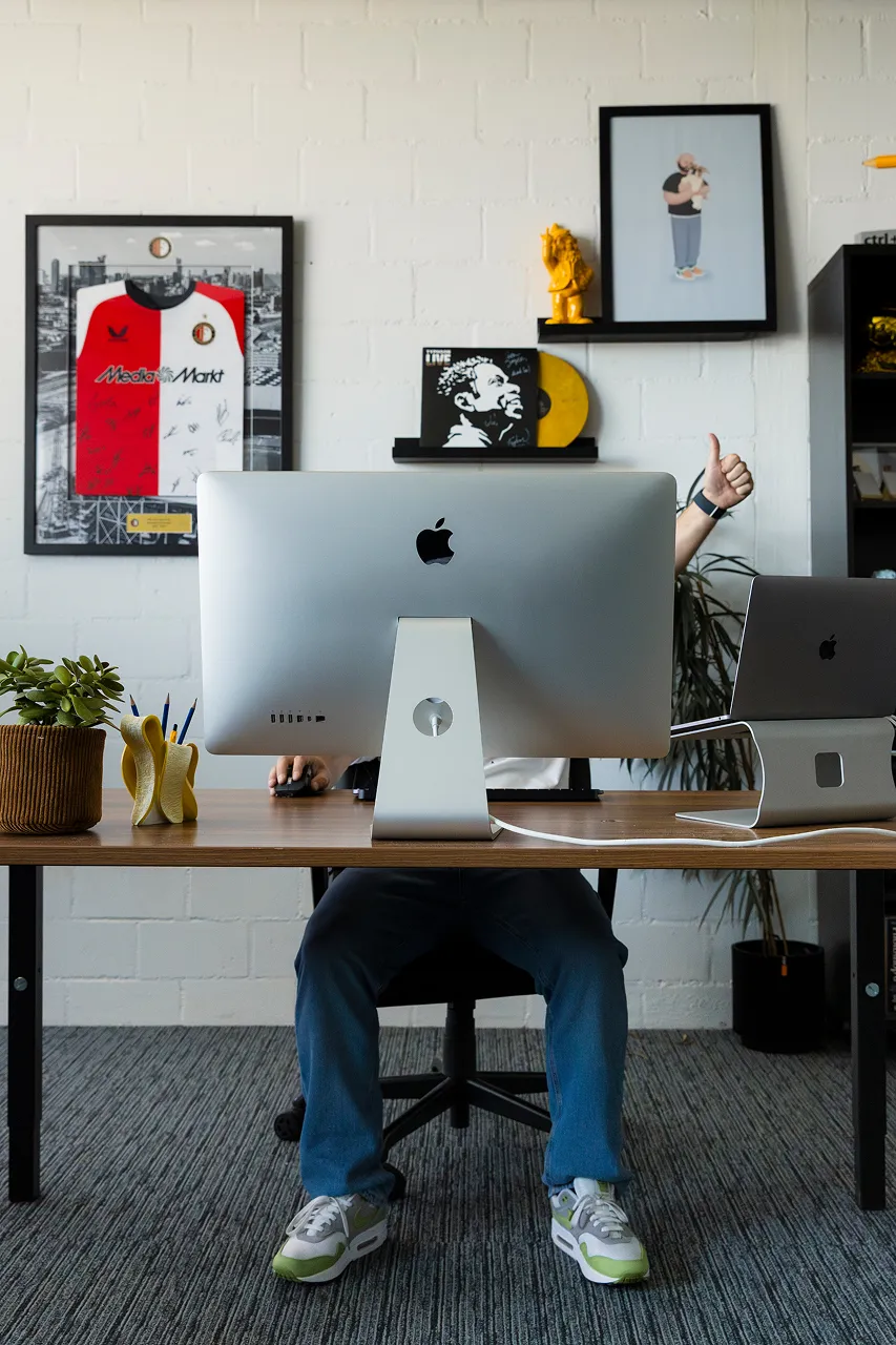 Medewerker van Brandlos zit achter de computer aan het bureau en steekt een duim omhoog