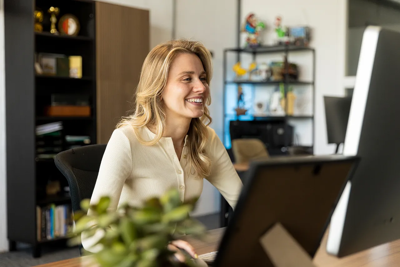 Een medewerker van Brandlos zit achter de computer en lacht naar haar scherm
