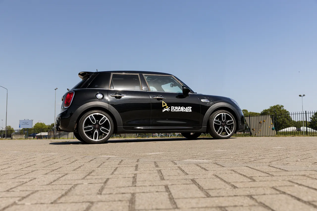 Een zwarte mini Cooper met gele lijnen en het logo van brandlos op de zijkant.