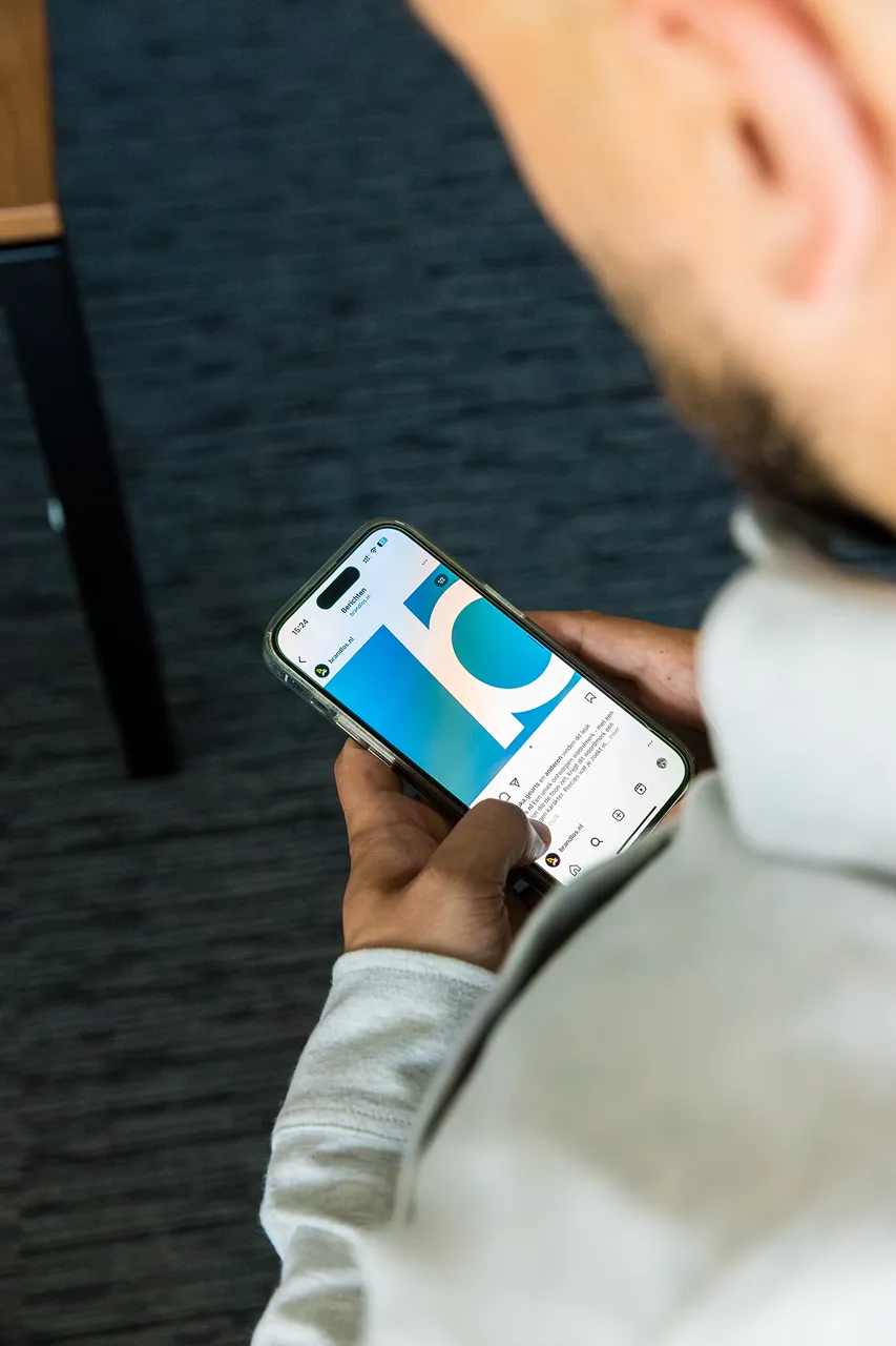Een medewerker van Brandlos heeft een telefoon vast met een Instagram post van brandlos