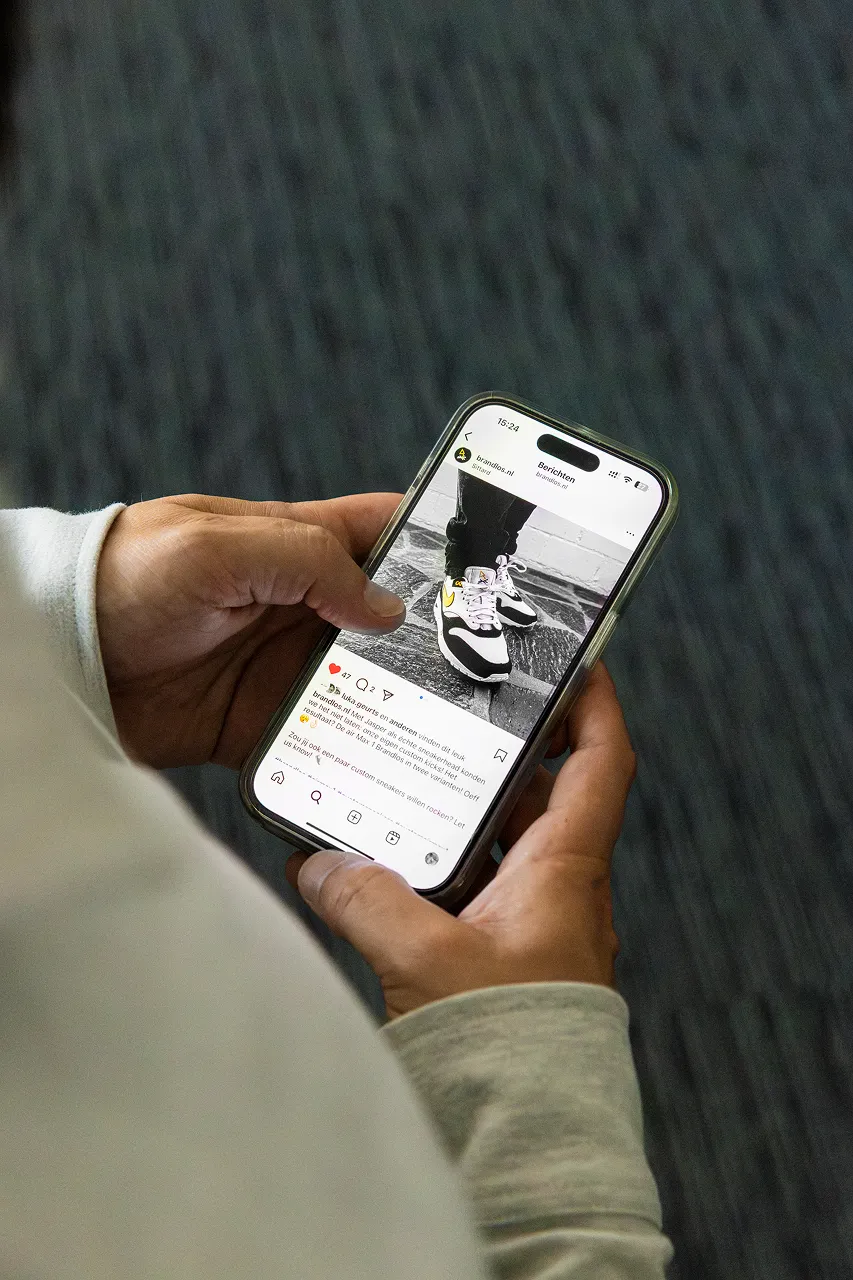 Een medewerker van Brandlos heeft een telefoon vast met een Instagram post van brandlos