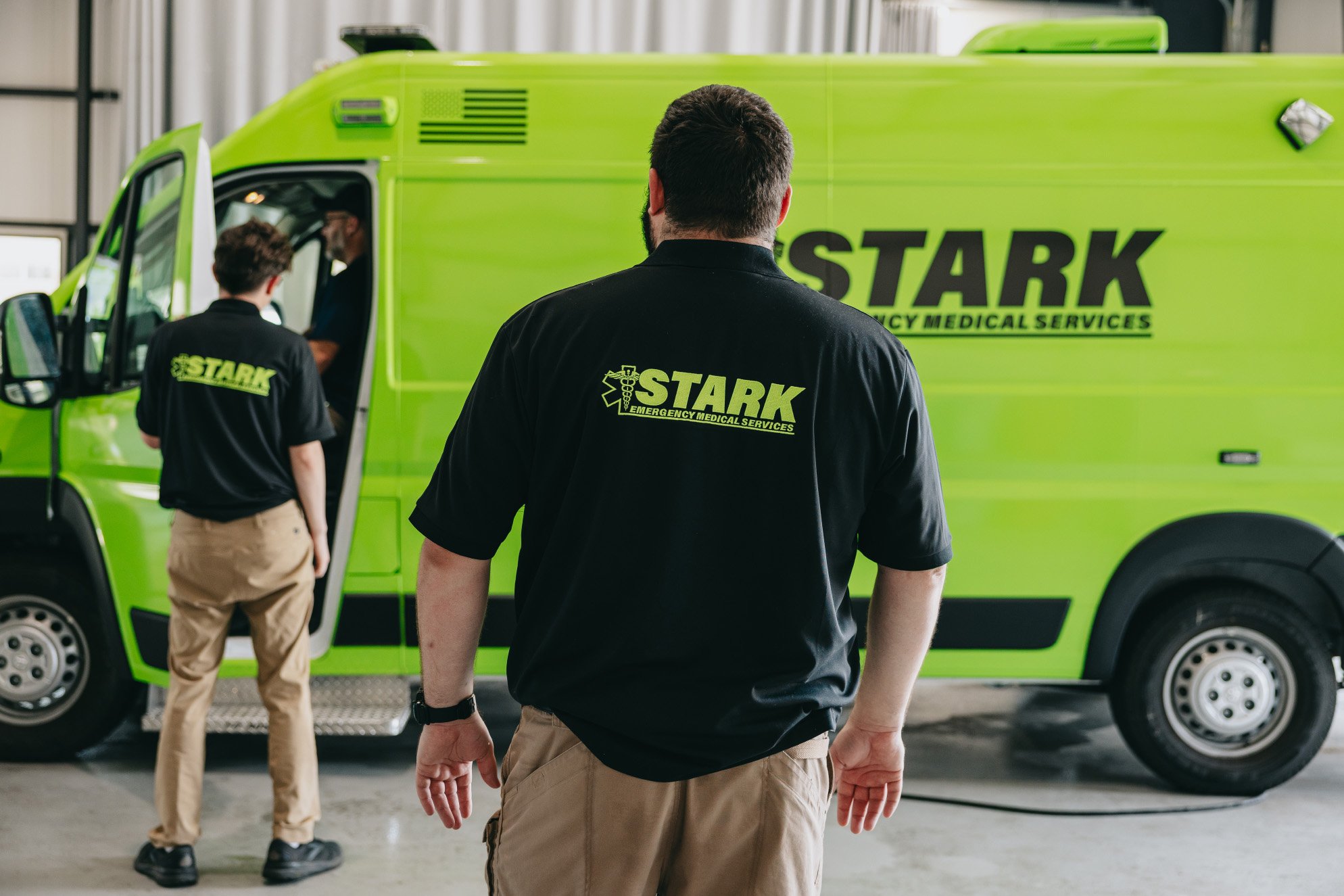 Two Stark County Ambulance crew members staged beside a unit outdoors