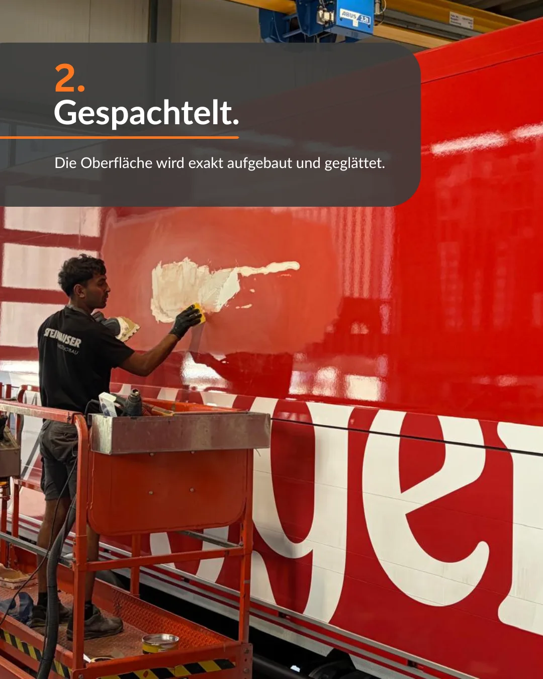 Schritt 2: Gespachtelt. Mitarbeiter traegt Spachtelmasse auf den roten Aufbau auf, die Oberflaeche wird geglaettet