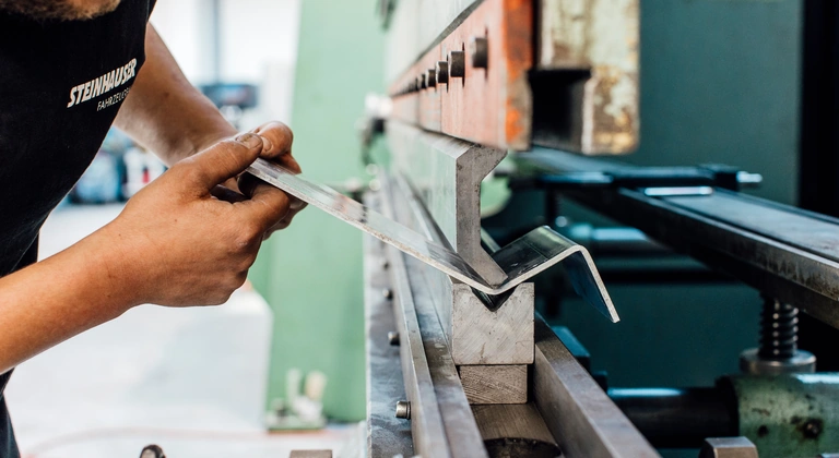 Mitarbeiter biegt ein Blechprofil an der Kantbank