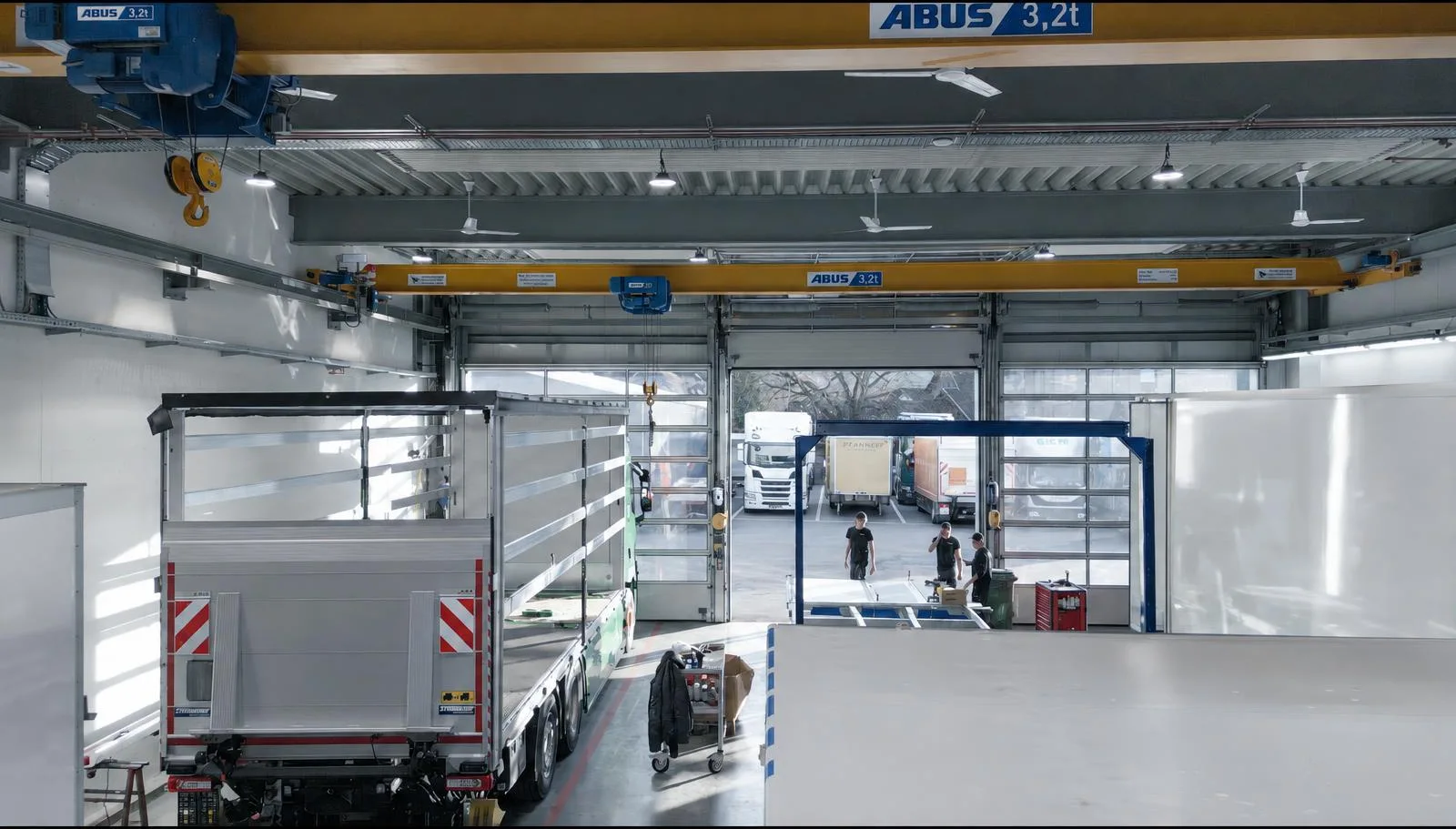 Blick in die Werkshalle mit Hallenkran und Fahrzeugaufbauten