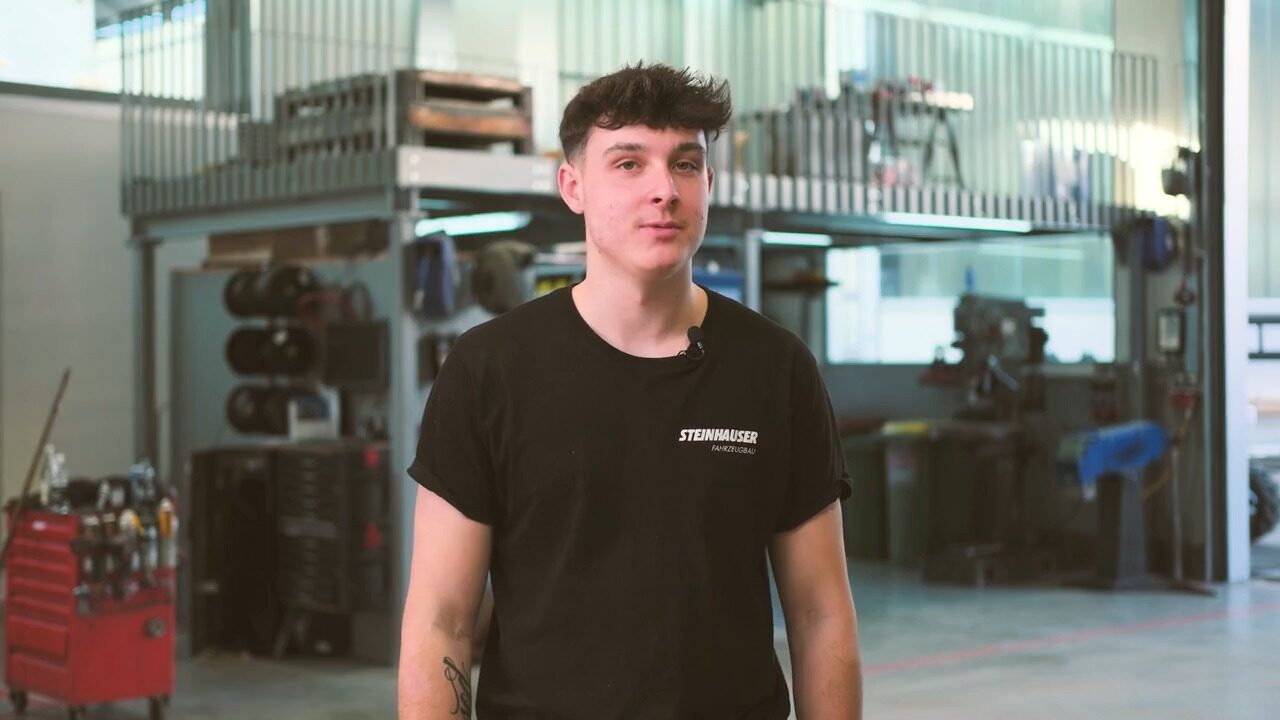 Andras steht in der Werkstatt und spricht in die Kamera