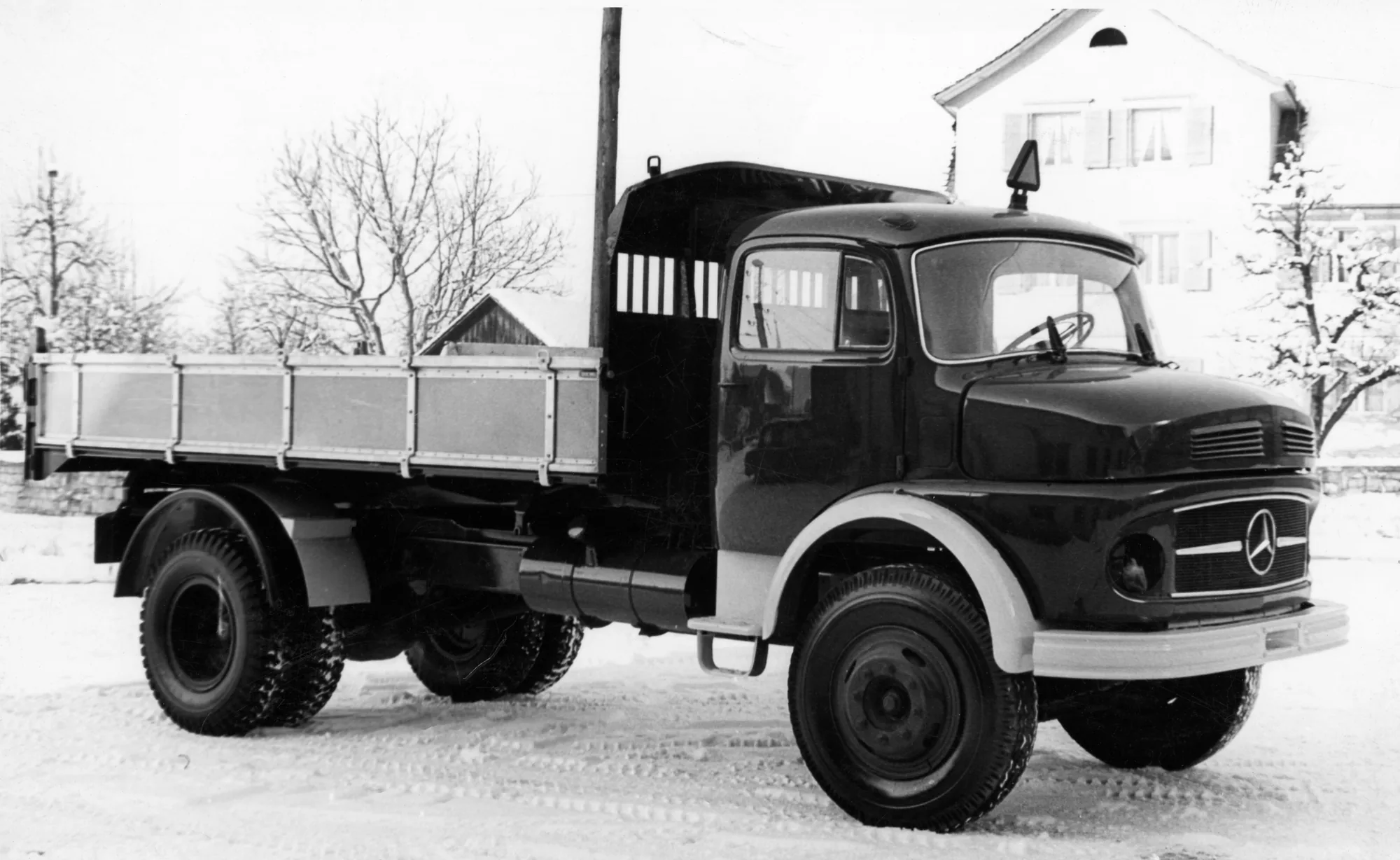 Kipper-Lkw in Schwarzweiss vor verschneitem Haus