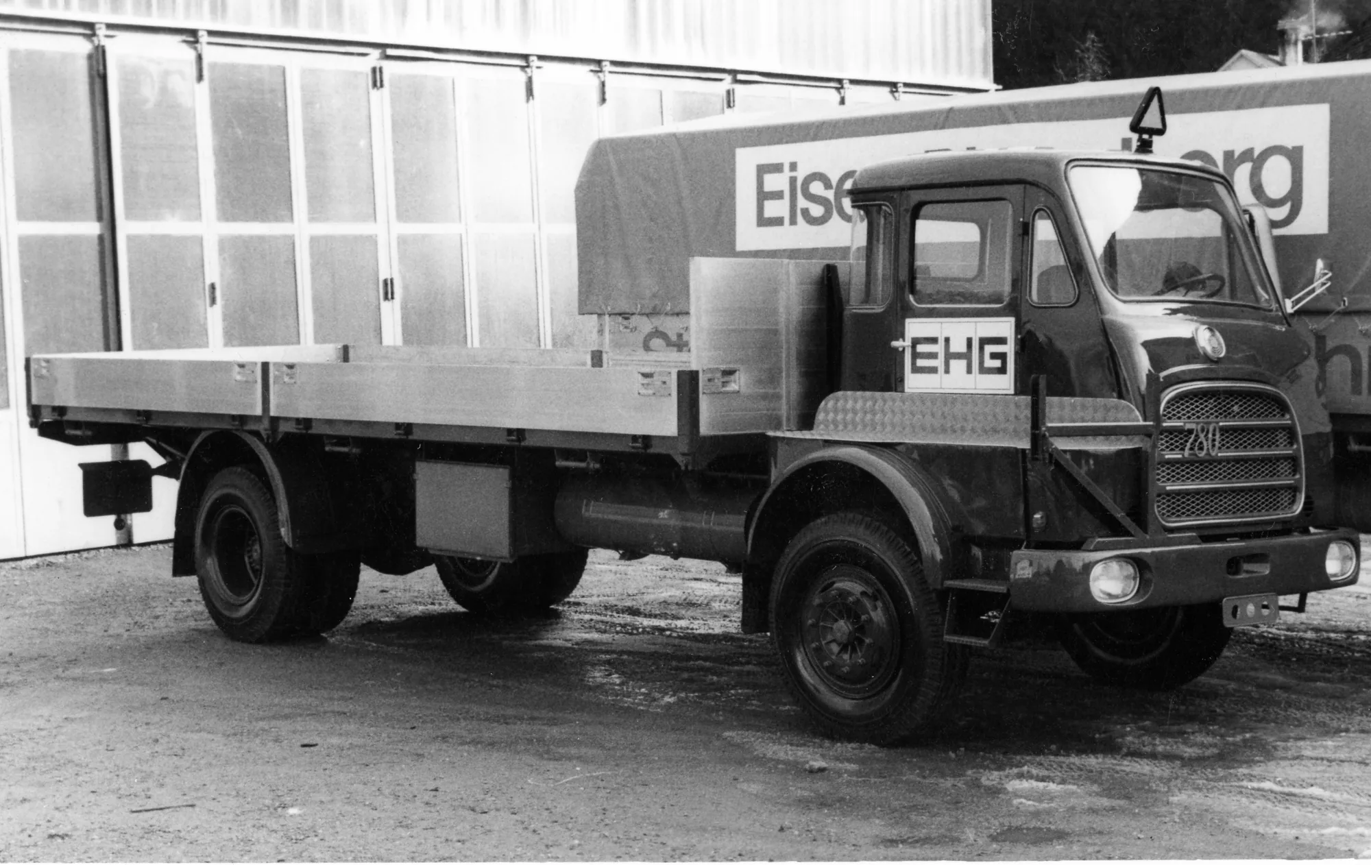 Pritschen-Lkw mit EHG-Schild vor einer Halle, Schwarzweiss