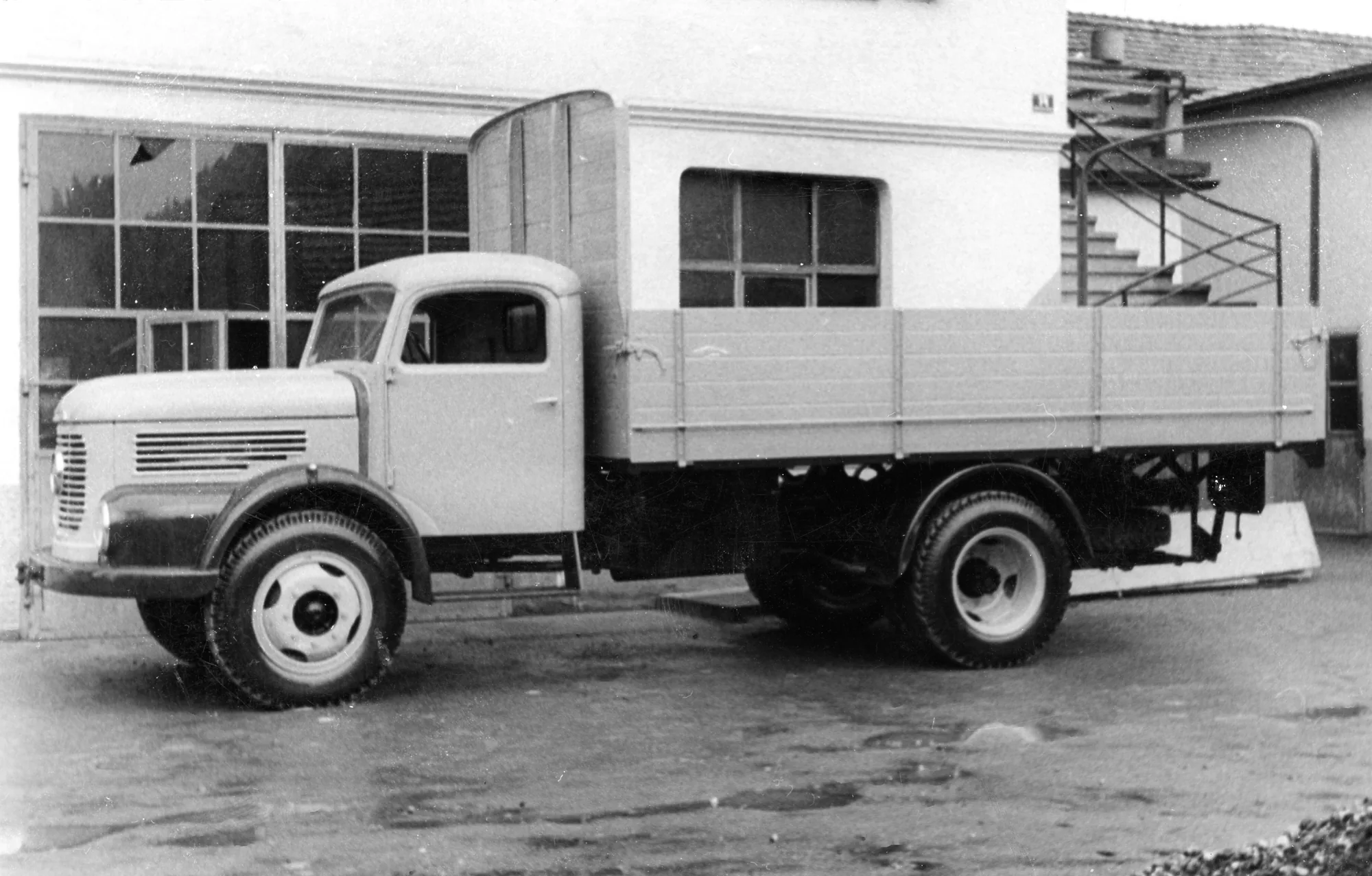 Lkw mit Pritschenaufbau vor einer Halle, Schwarzweiss