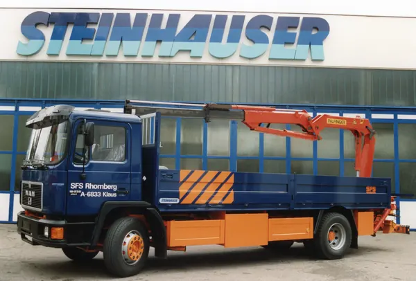 Blau-oranger MAN mit Ladekran vor dem Steinhauser-Gebäude