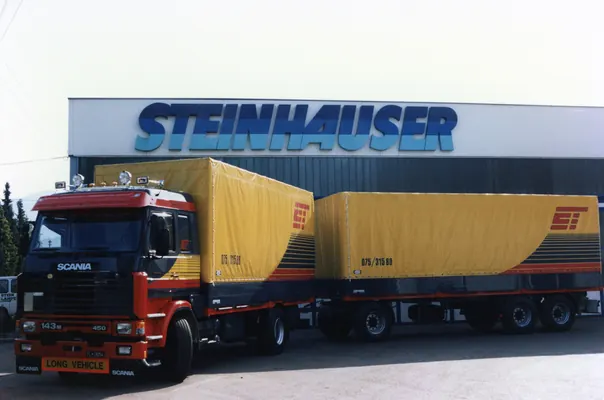 Scania-Hängerzug mit gelben Planenaufbauten vor dem Steinhauser-Gebäude