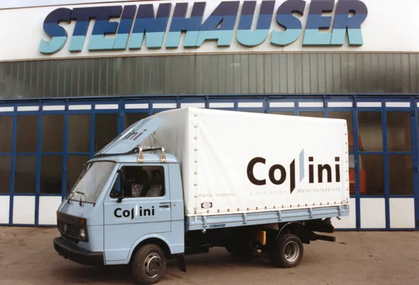 Hellblauer Kleintransporter mit Planenaufbau von Cosini vor dem Steinhauser-Gebäude