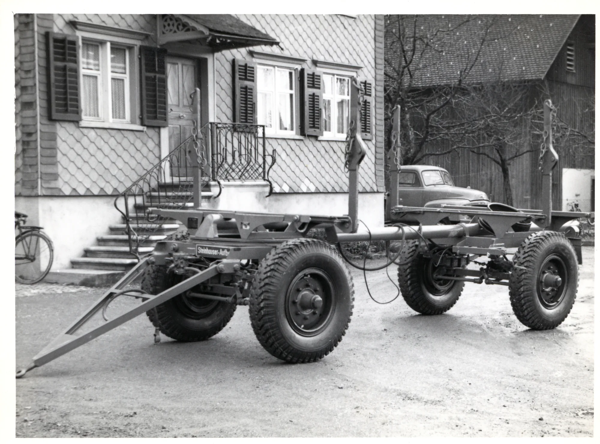 Anhänger-Fahrgestell vor einem Haus, Schwarzweiss