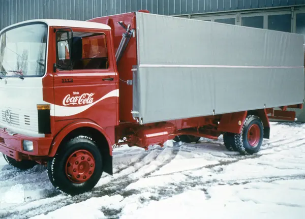 Roter Lkw mit Coca-Cola-Beschriftung und Pritschenaufbau im Schnee