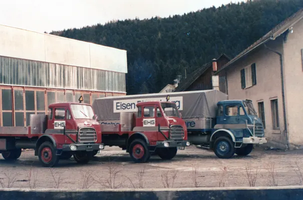 Drei Lkw vor der Werkstatt, einer mit Planenaufbau
