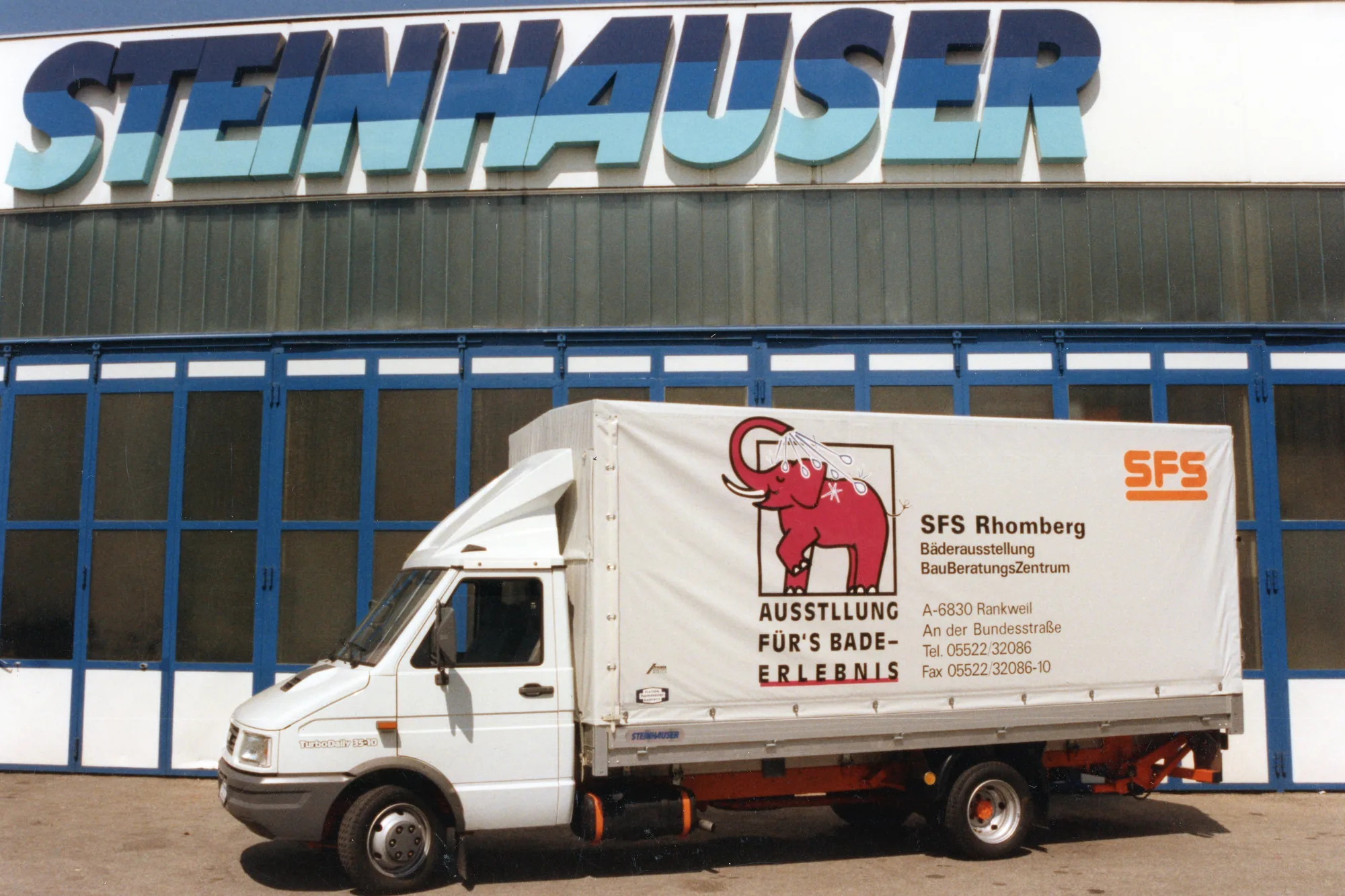 Kleintransporter von SFS Rhomberg mit Planenaufbau vor dem Steinhauser-Gebäude