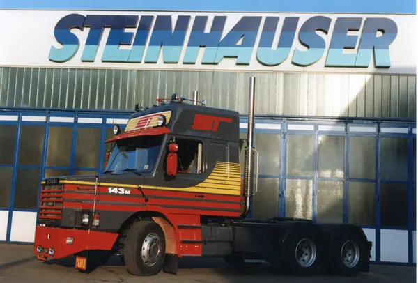 Scania-Sattelzugmaschine mit Streifendekor vor dem Steinhauser-Gebäude