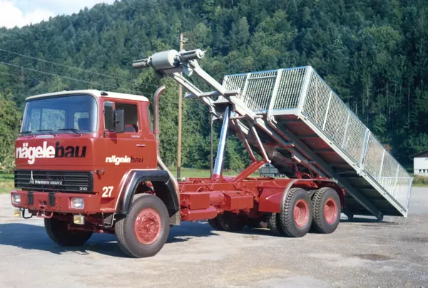 Roter Dreiachser von Nägele Bau mit Ladekran und gekipptem Gitteraufbau