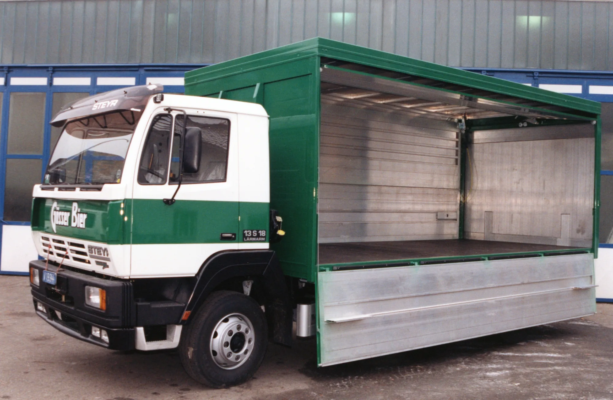Lkw mit grünem Getränkeaufbau und geöffneter Seitenwand