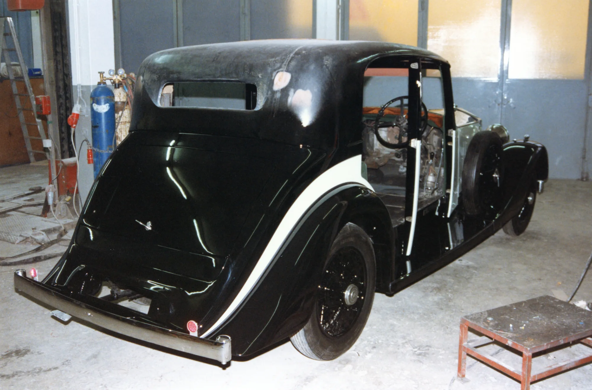 Schwarz lackierter Oldtimer in der Lackierkabine