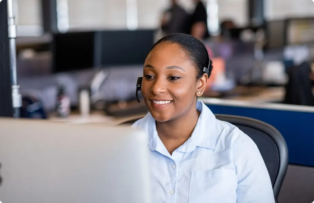 Smiling support agent with a headset working at her desk