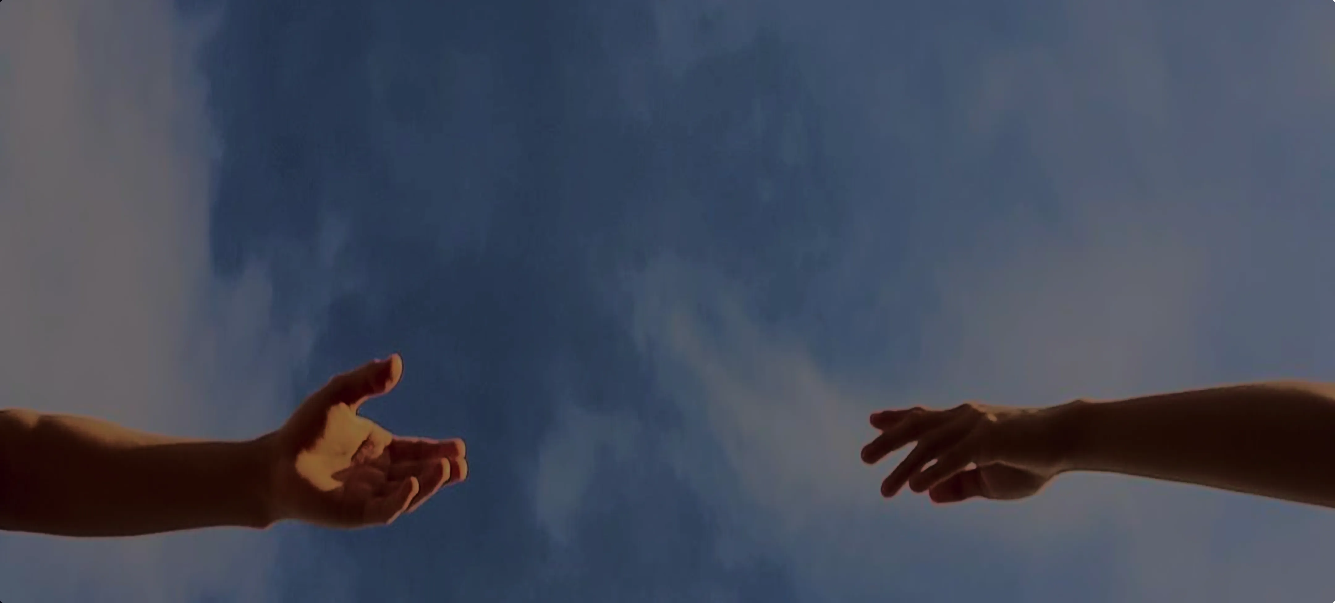 Two hands reaching toward each other against the sky