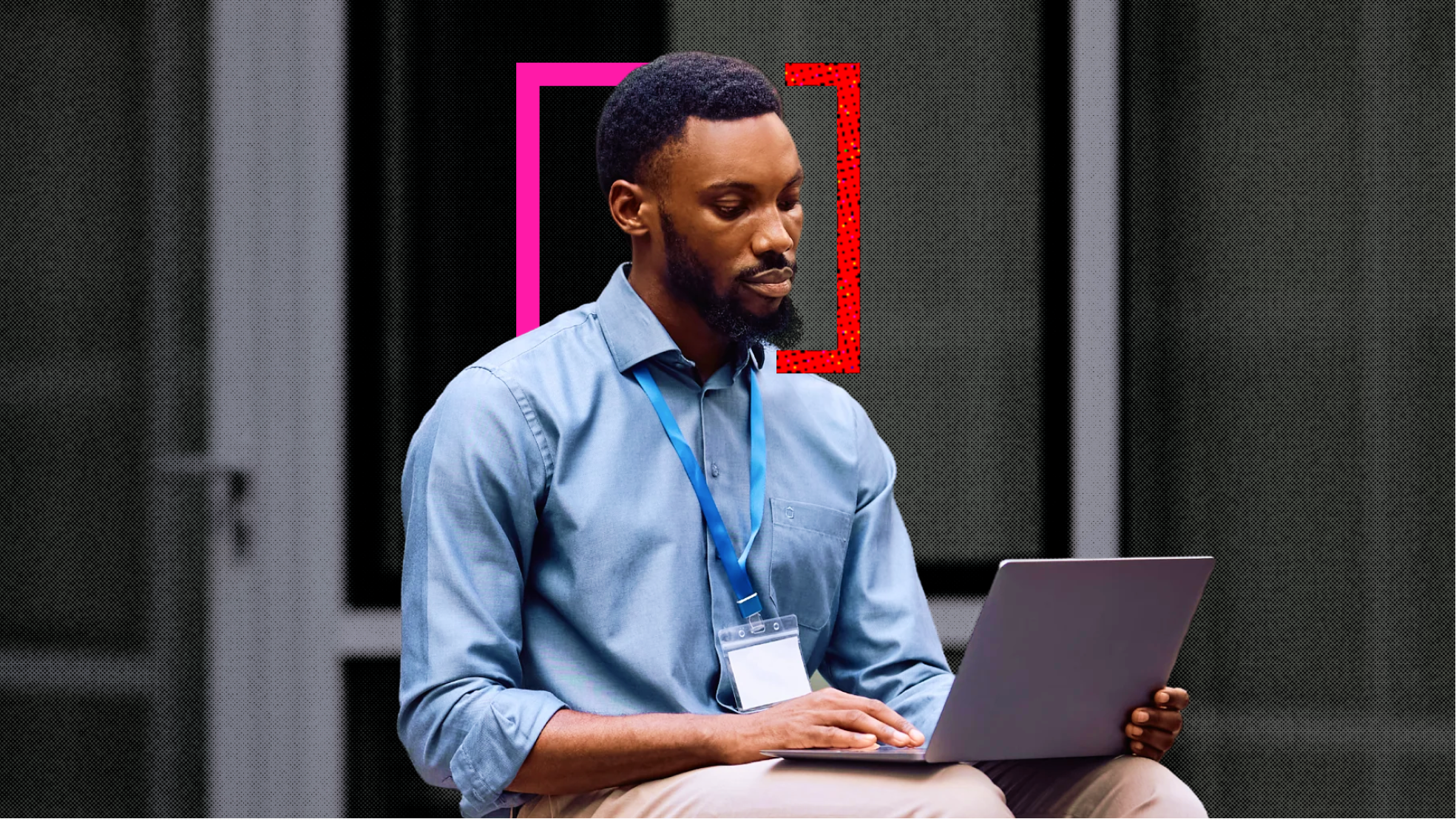 A man in a blue shirt and lanyard works on a laptop in an office, framed by pink and red bracket shapes in the nudge brand style.