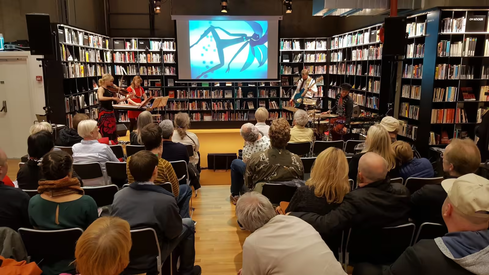 Audience at a REX screening among bookshelves