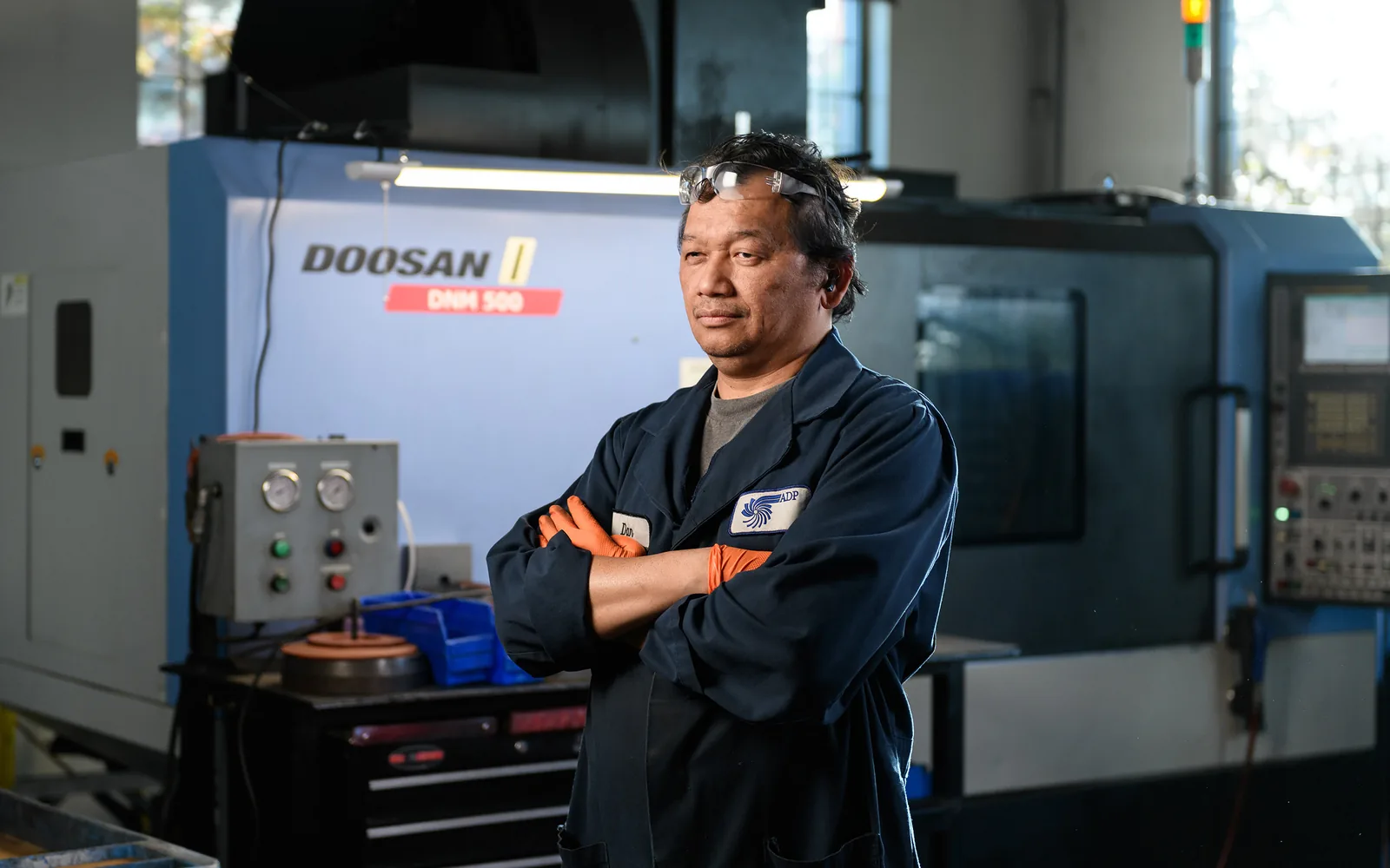 Automotive technician standing in a machine shop beside a lathe