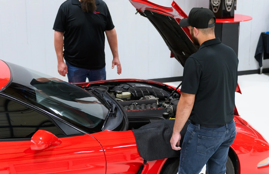 Cloyes technicians working on a red sports car, shown as a tiled mosaic