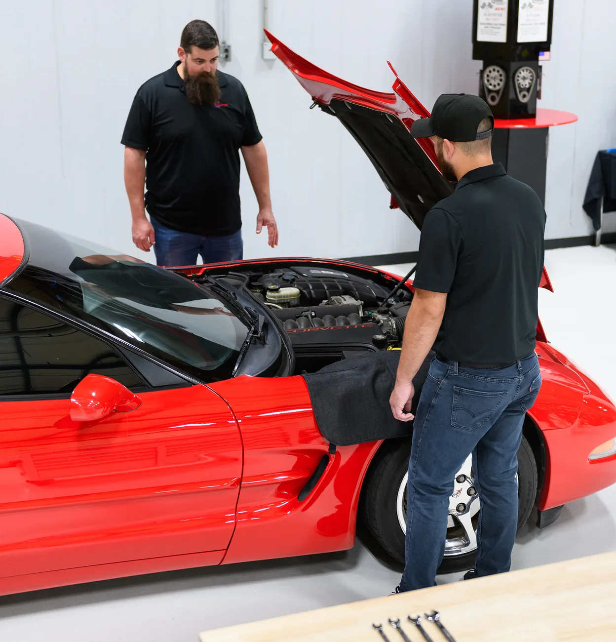 Cloyes engineers inspecting the engine bay of a red Corvette