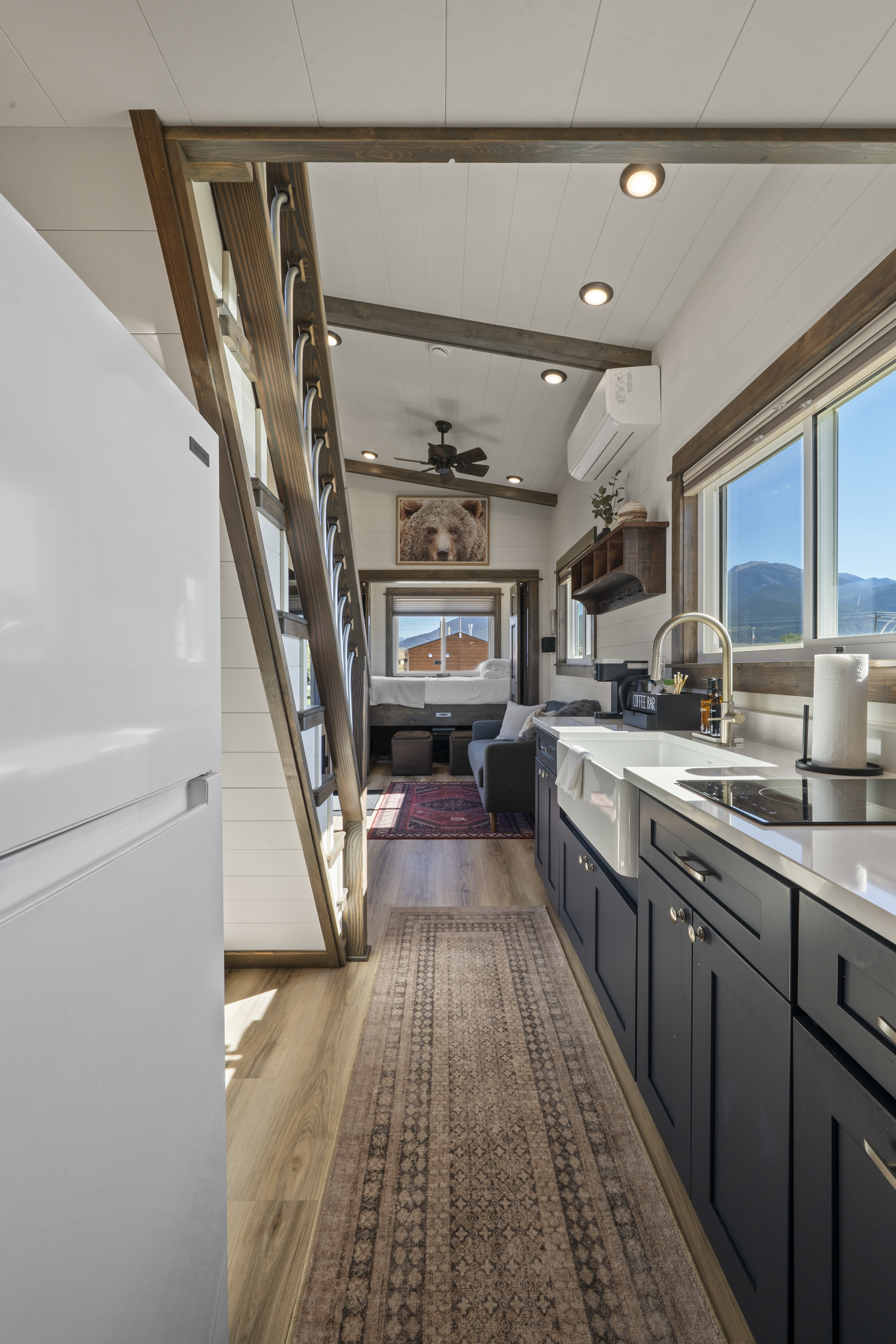 Royal Wulff galley kitchen with navy cabinets, farmhouse sink and loft stairs, looking toward the living room