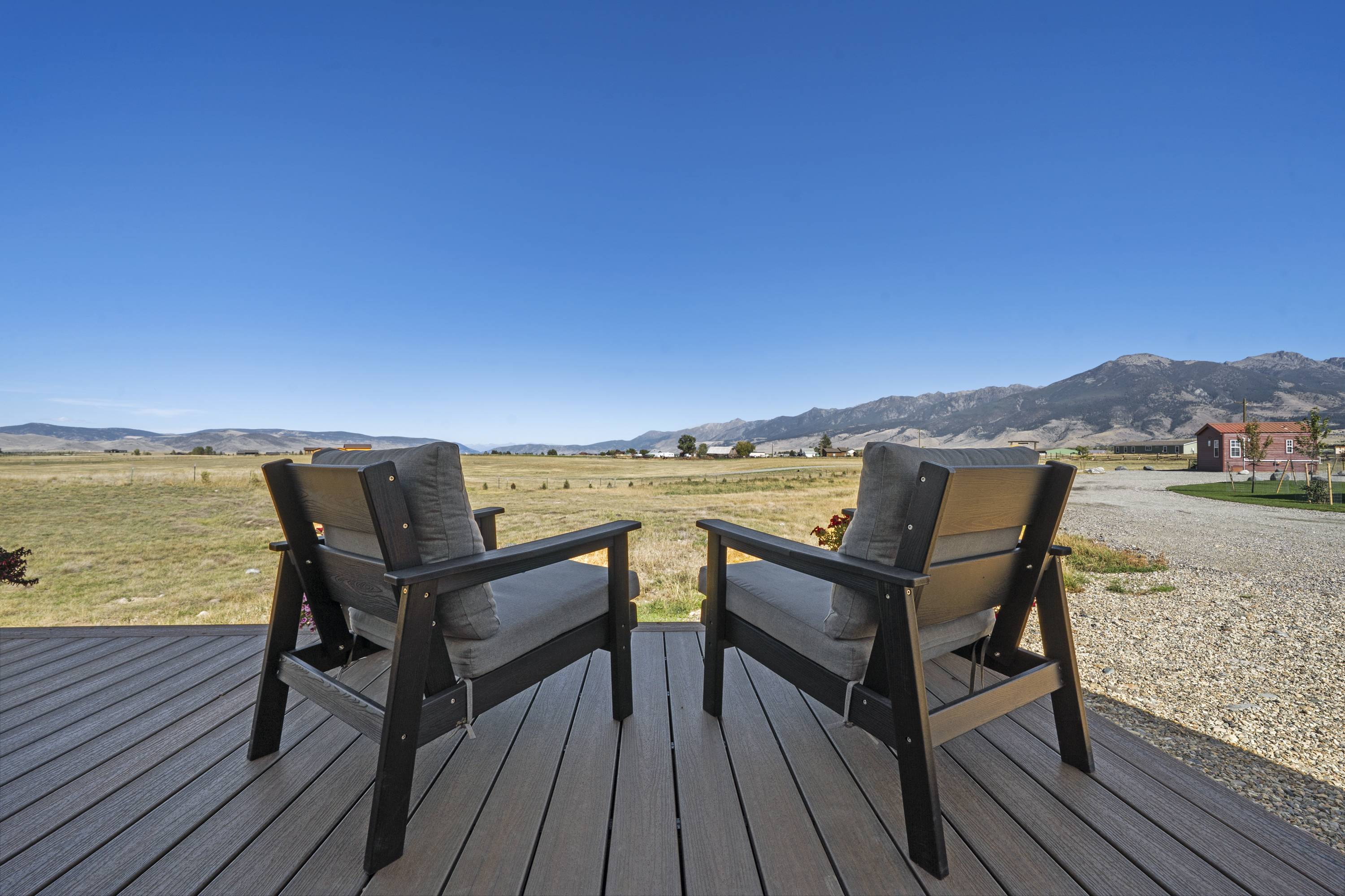 Two cushioned chairs on the Royal Wulff deck facing open range and mountains