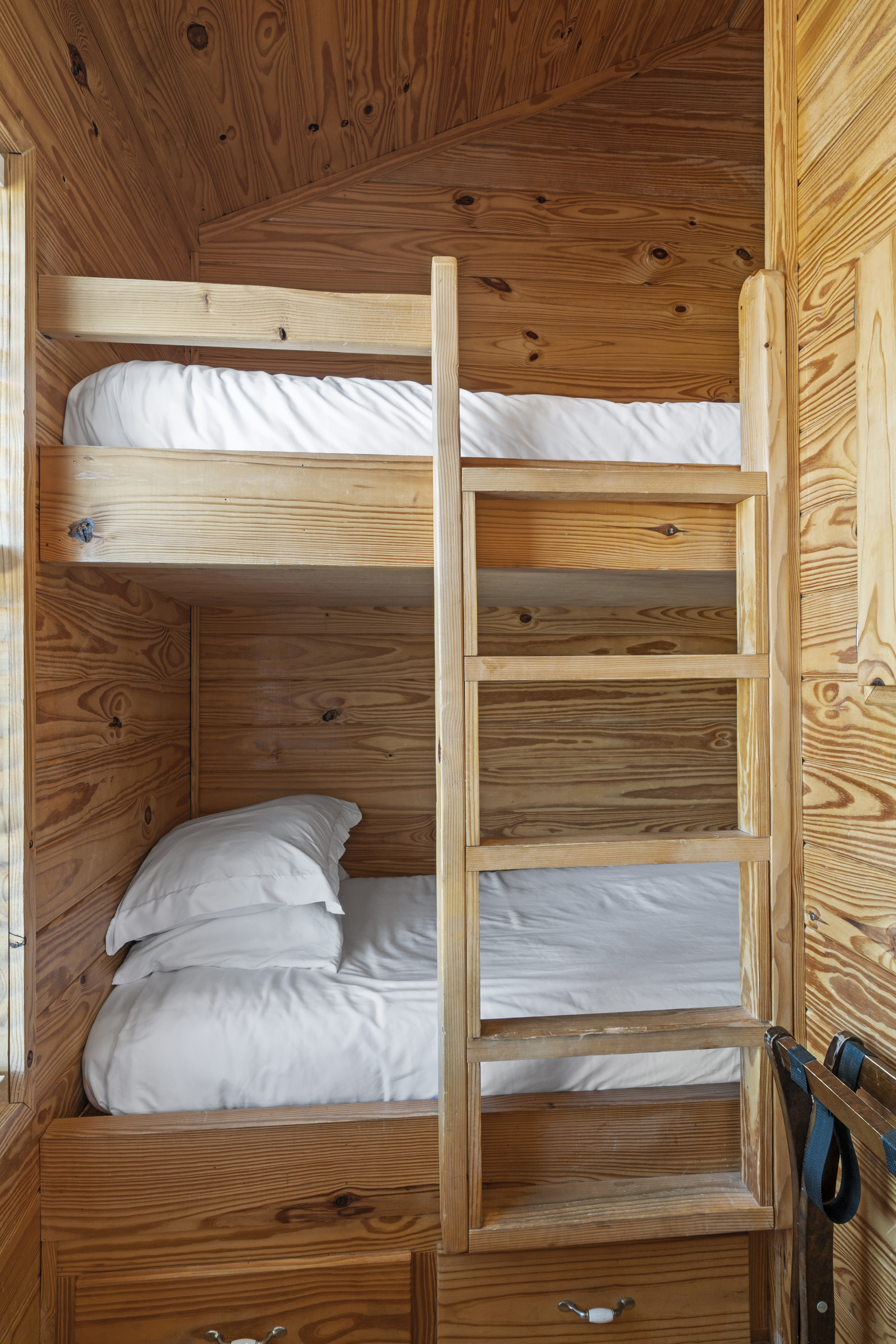 Built-in pine bunk beds with a ladder and storage drawers