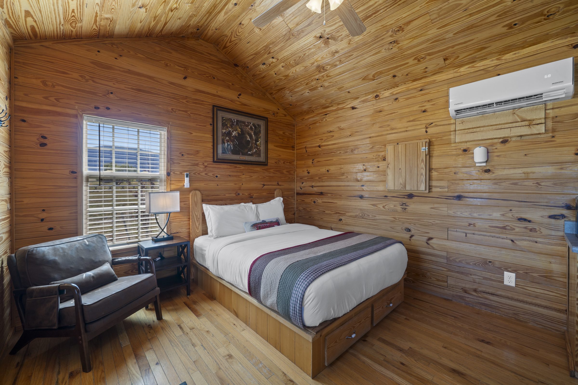 Cabin queen bed with storage drawers, a reading chair and a mini-split heating and cooling unit