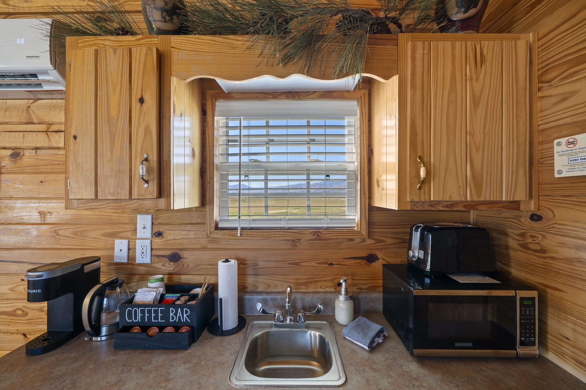 Kitchenette sink under a window, with a Keurig coffee bar, toaster and microwave