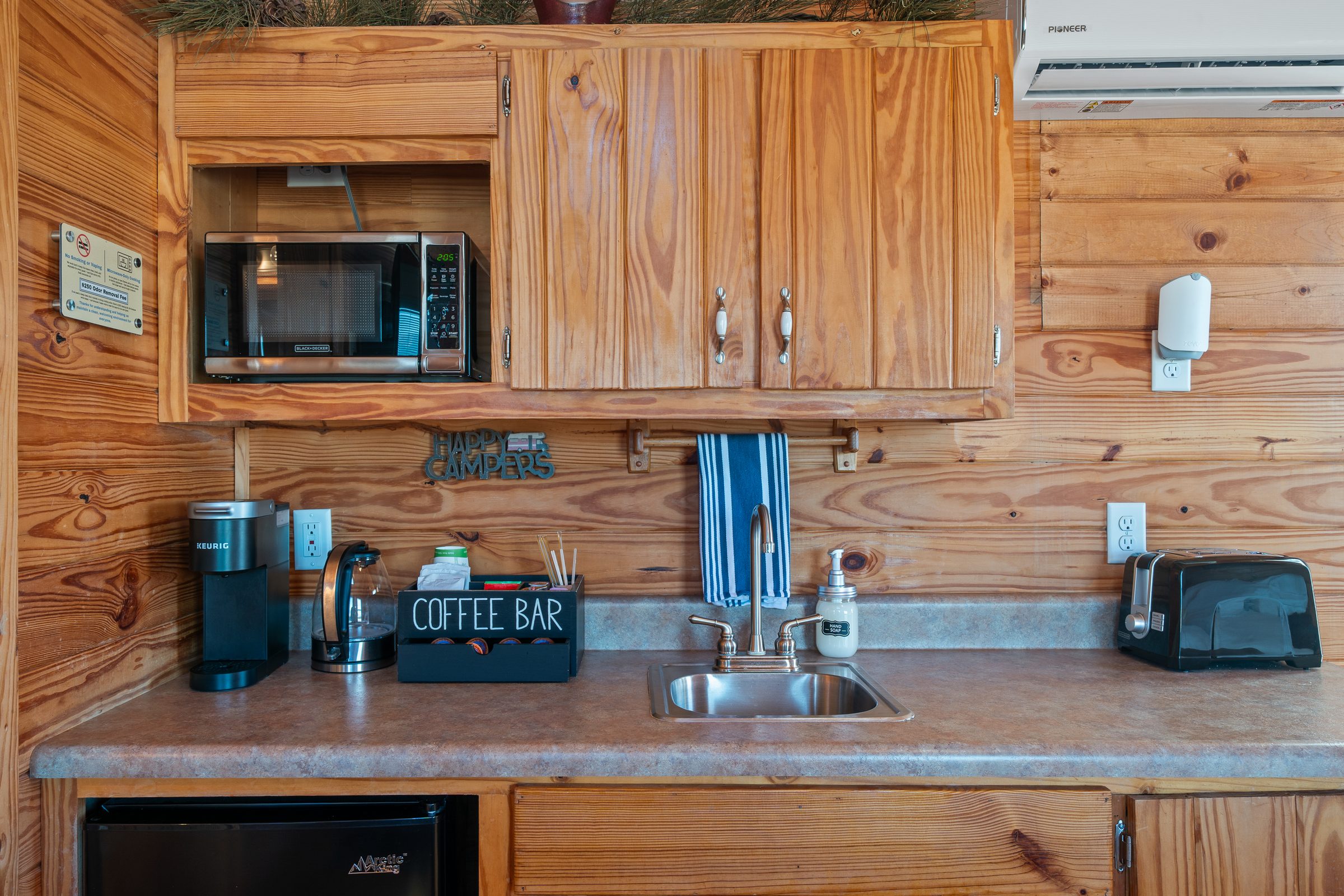 Kitchenette counter with a Keurig, coffee bar, sink and toaster under pine cabinets