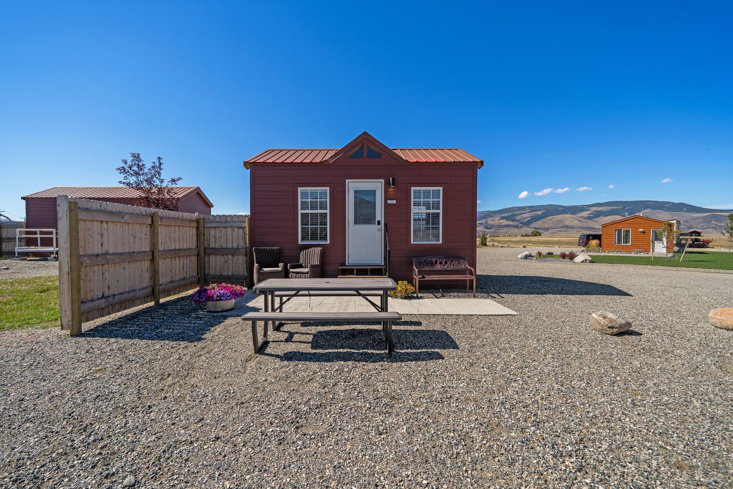Caddis Cabin, with a concrete patio, picnic table, two wicker chairs and a Welcome bench