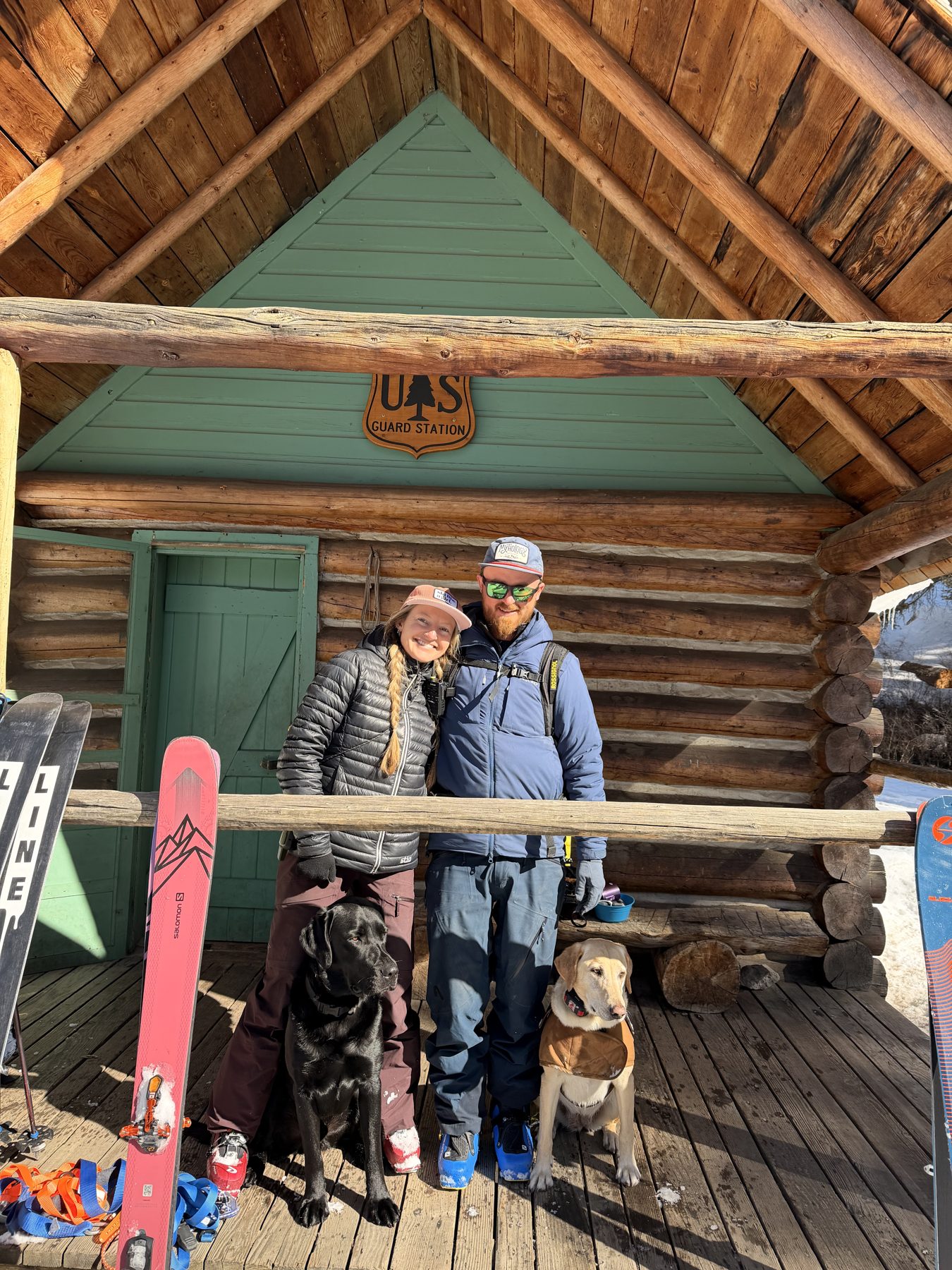 EJ and Natalie with their labs, Honey and Bo, on the porch of a log cabin