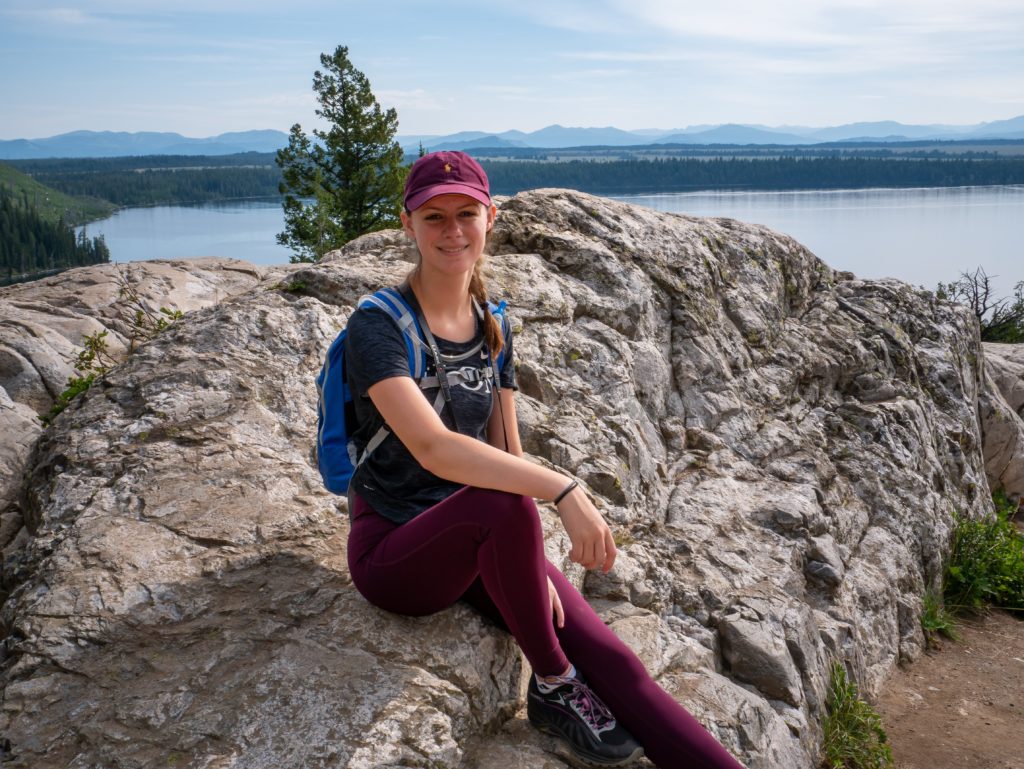Ashley sitting on a rock outcrop above a lake